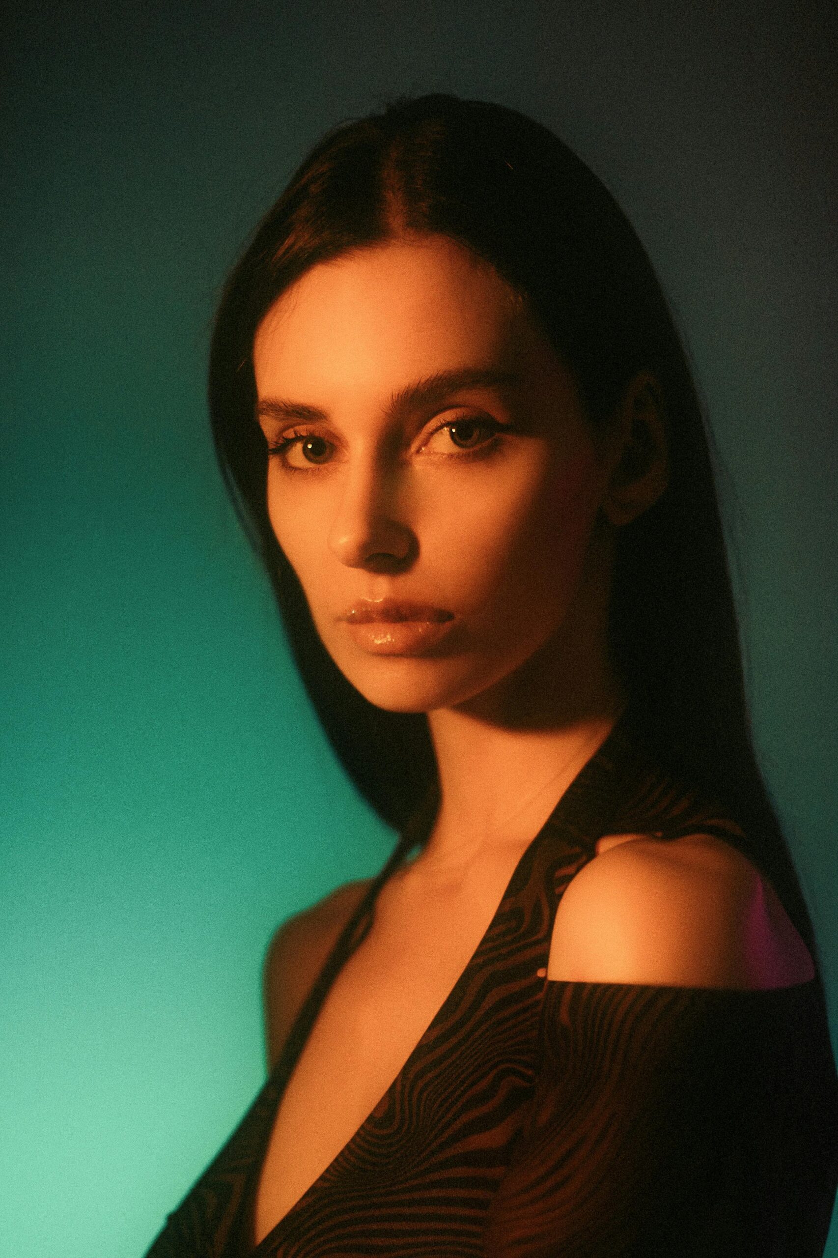 A striking portrait of a woman with expressive eyes against a green gradient background.